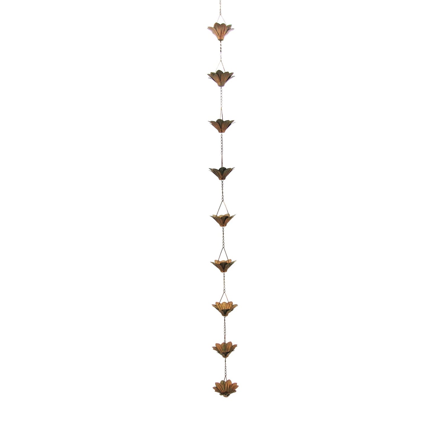 A bronze metal garden wind chime shaped like lotus flowers hanging from a tree branch with blooming pink and white flowers in the background.