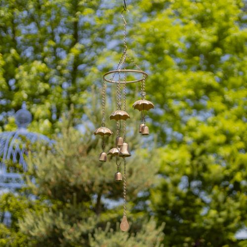 Decorative wind chime with hanging bells against a green tree background