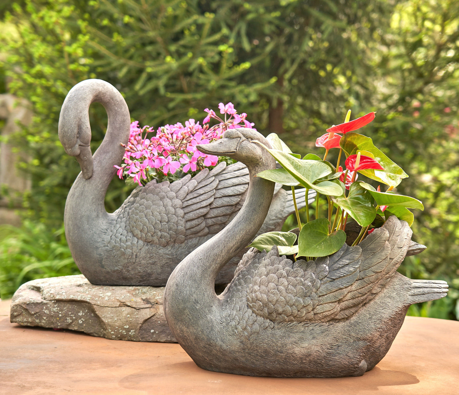 Swan-shaped decorative garden planter filled with flowers in an outdoor setting