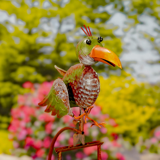 Decorative metal bird sculpture with a colorful beak against a blurred garden background