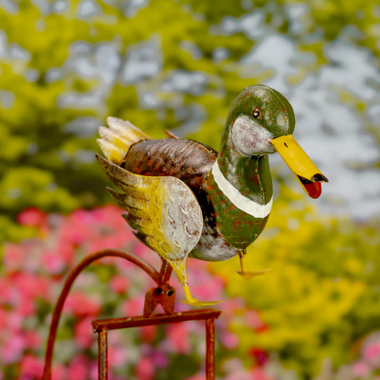 Decorative metal duck sculpture with a blurred garden background