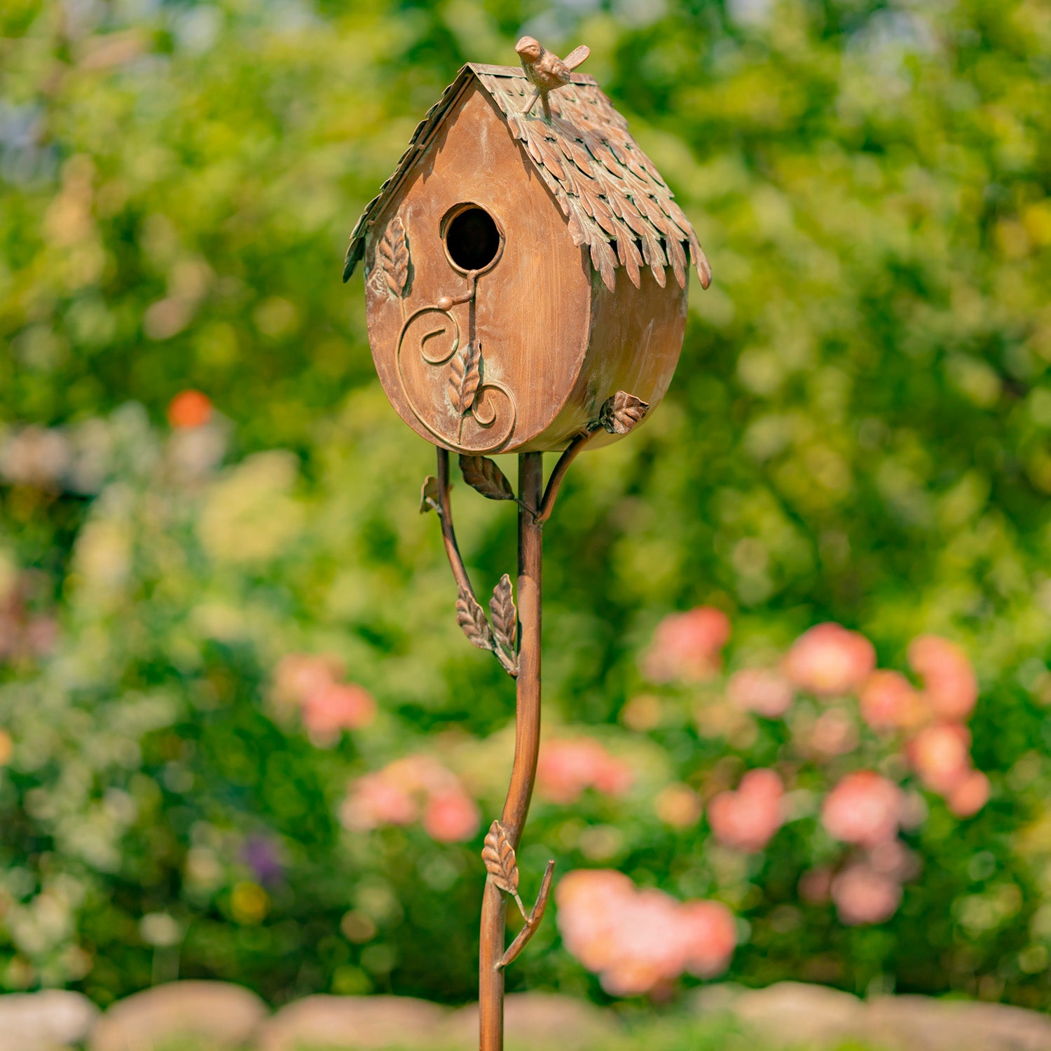 Decorative birdhouse on a stick with a blurred garden background