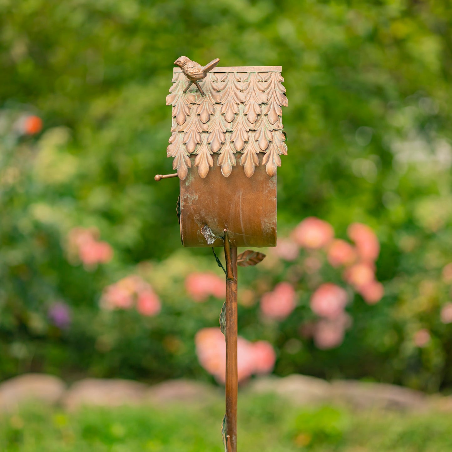 Decorative birdhouse on a stick with a blurred garden background