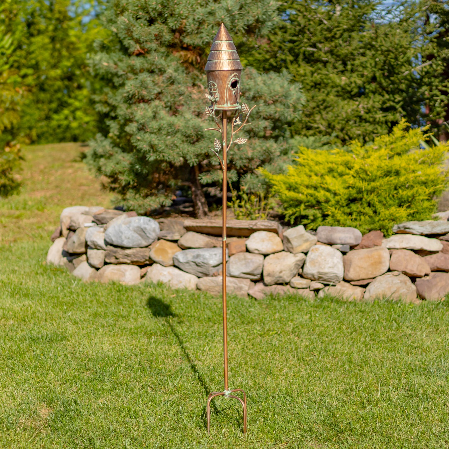Decorative copper garden stake with birdhouse in a garden setting