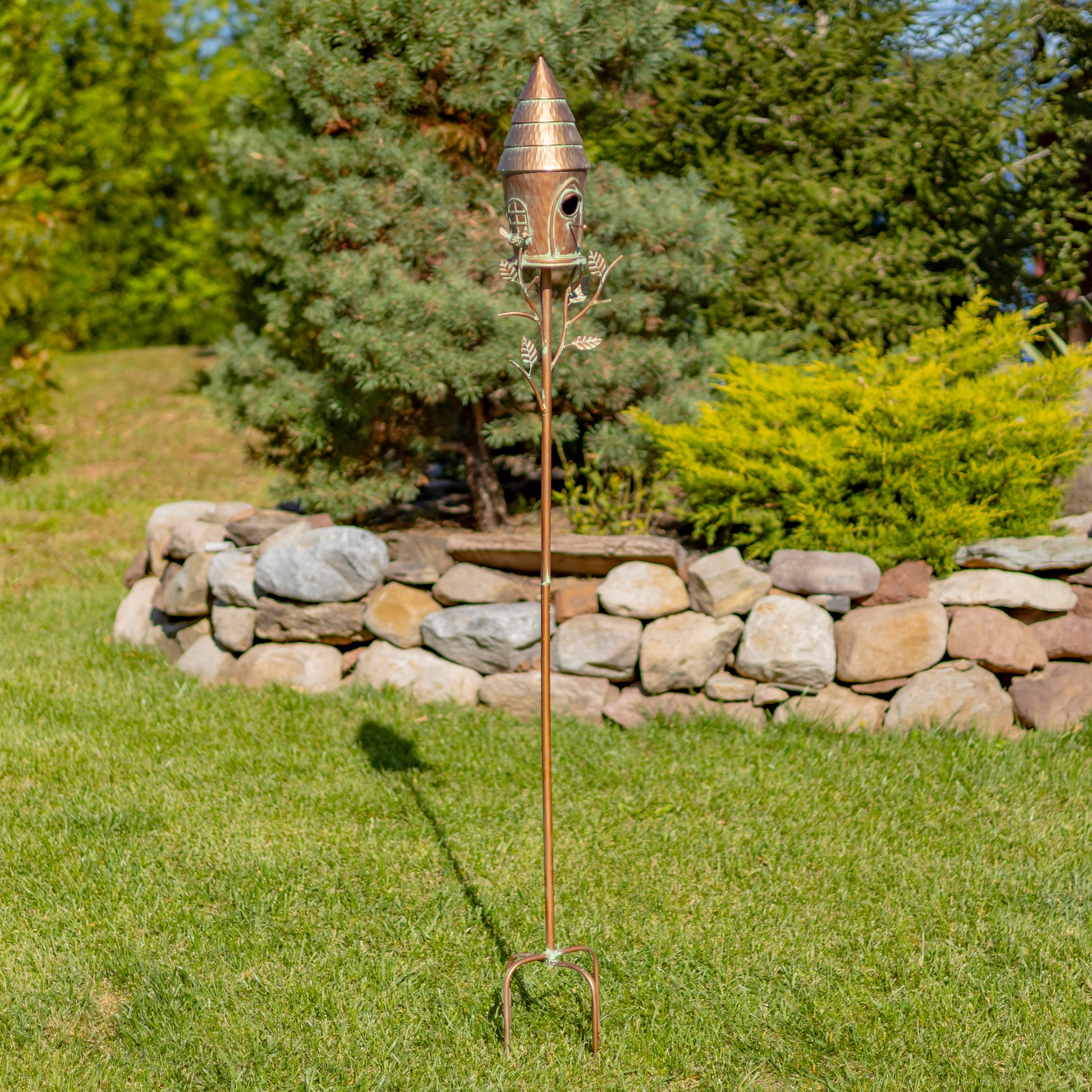 Decorative copper garden stake with birdhouse in a garden setting