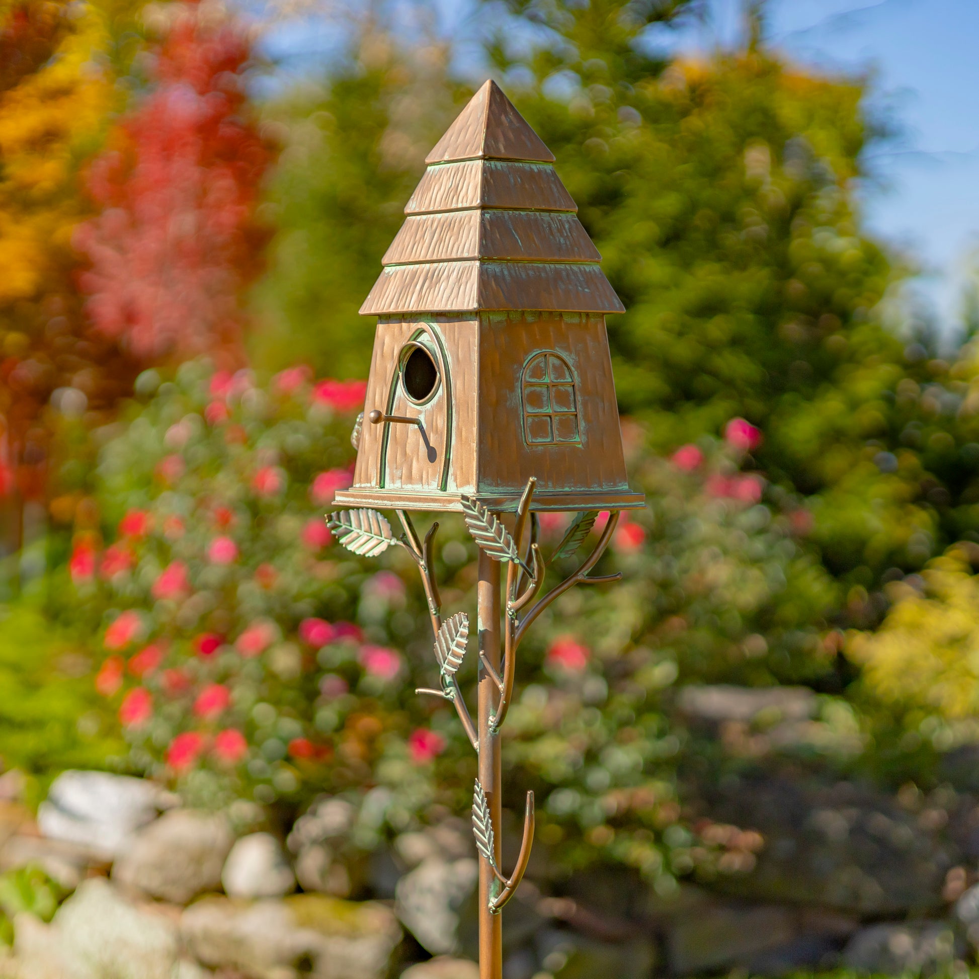Decorative birdhouse on a stand with a garden background