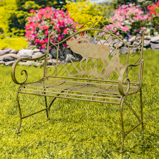 Decorative garden bench with a deer design on a grassy area with flowers in the background