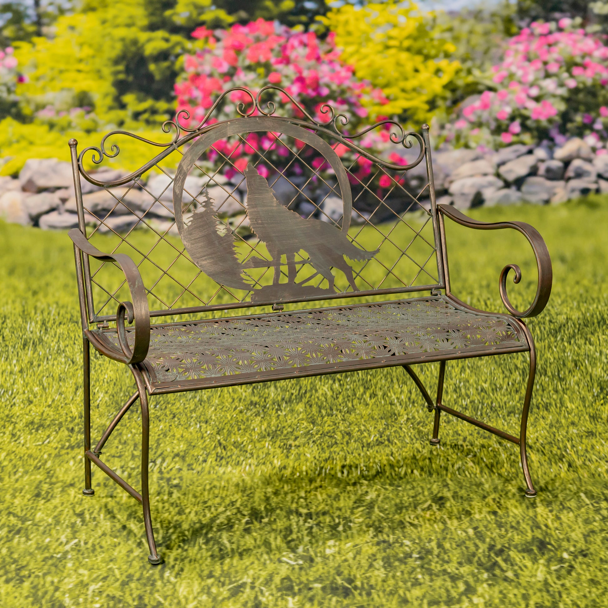 Decorative metal bench with peacock design on a grassy area with flowers in the background