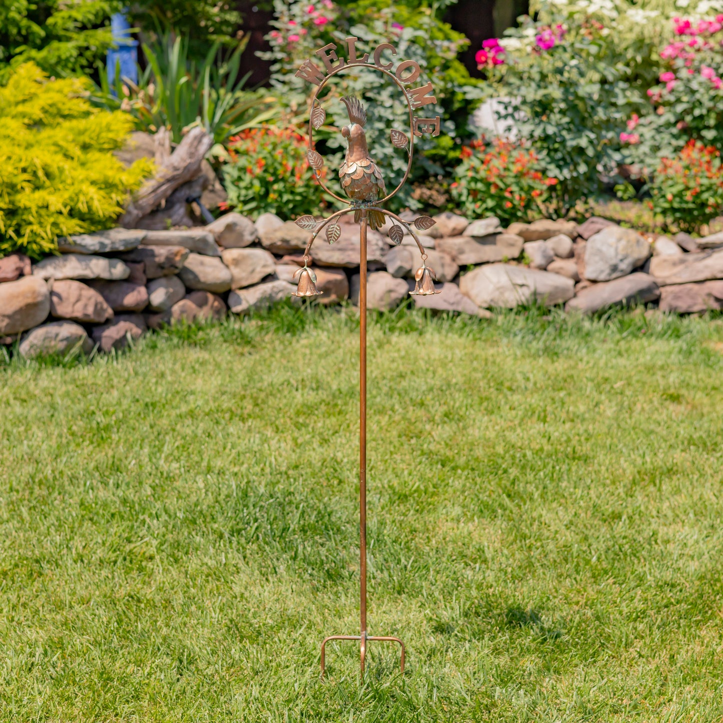 Decorative garden stake with metal sculpture on grass in a garden setting