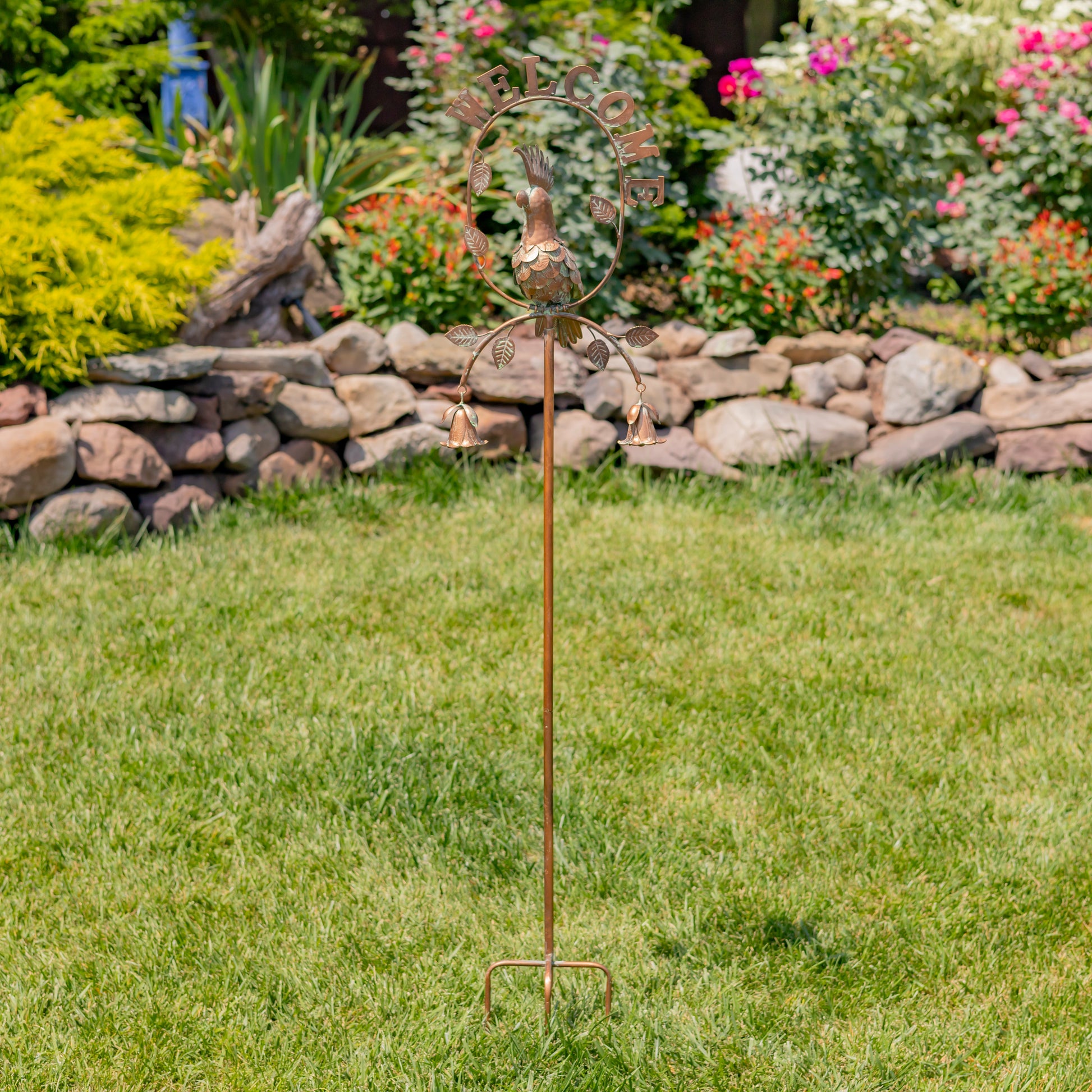 Decorative garden stake with metal sculpture on grass in a garden setting