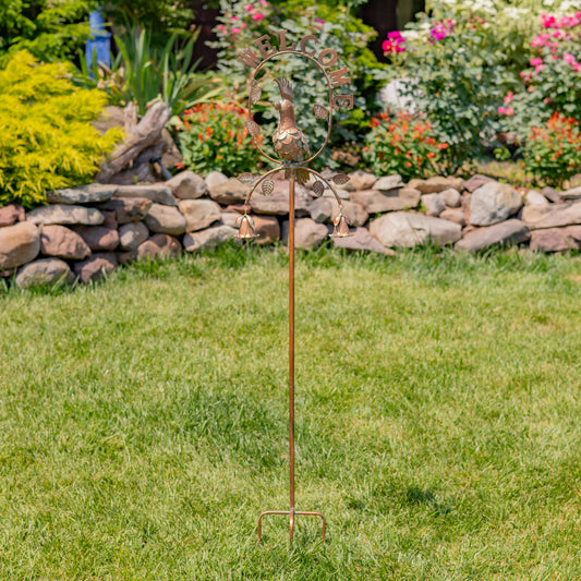 Decorative garden stake with metal sculpture on grass in a garden setting