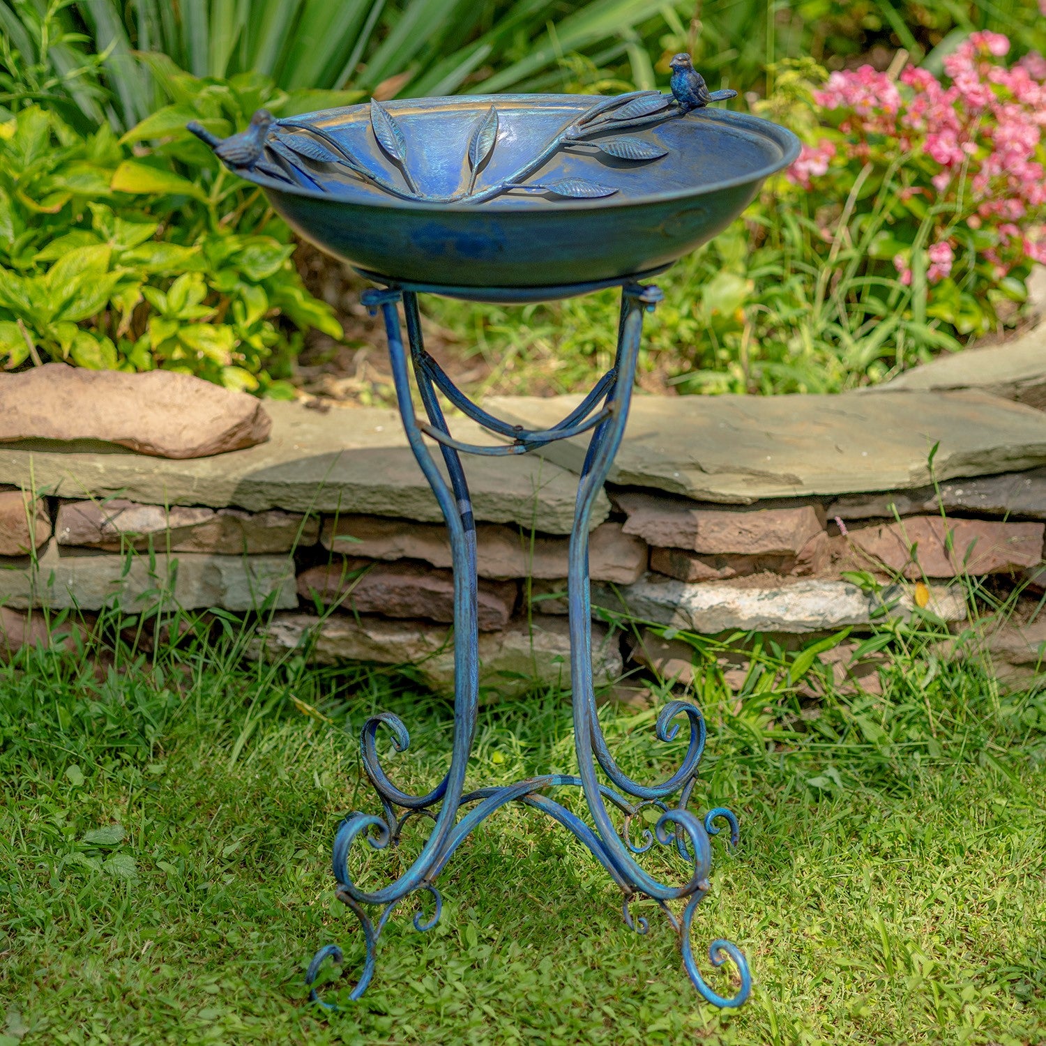 Decorative blue bird bath with stand in a garden setting