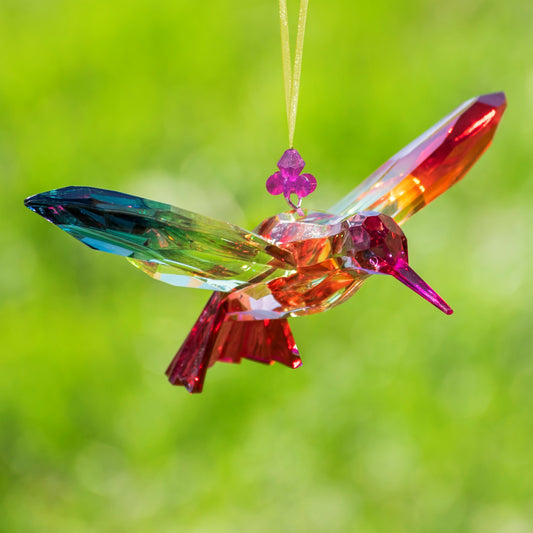 Colorful glass hummingbird ornament against a green background