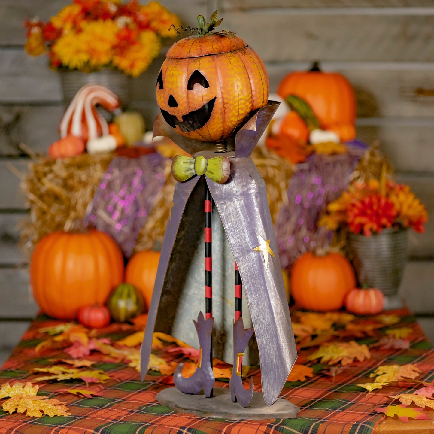 Decorative Halloween figure with a pumpkin head and sword, surrounded by pumpkins and autumn leaves.