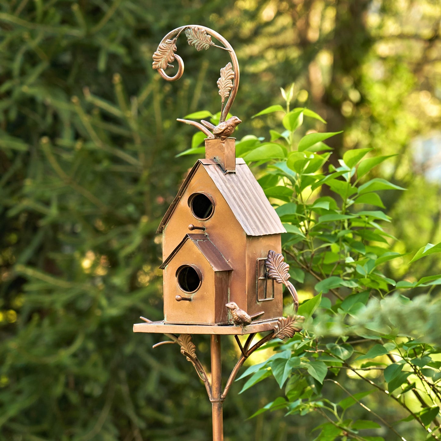 Decorative birdhouse on a stand with foliage in the background