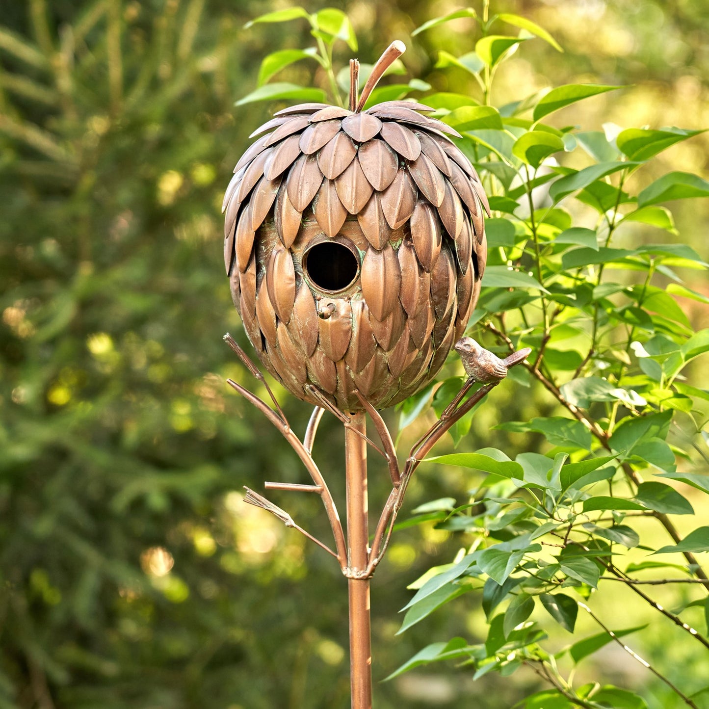 Copper colored pinecone shaped birdhouse on a stake