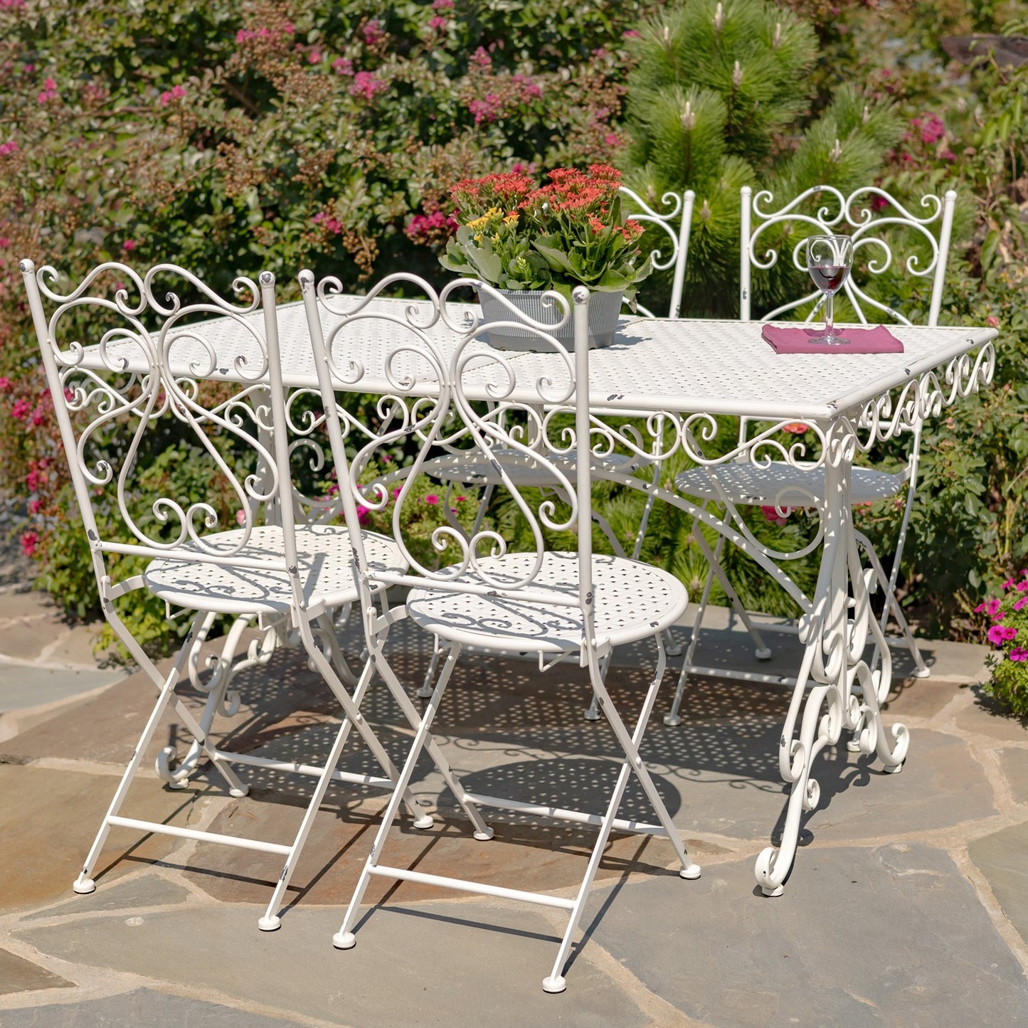 White metal outdoor furniture set with table and chairs on a stone patio
