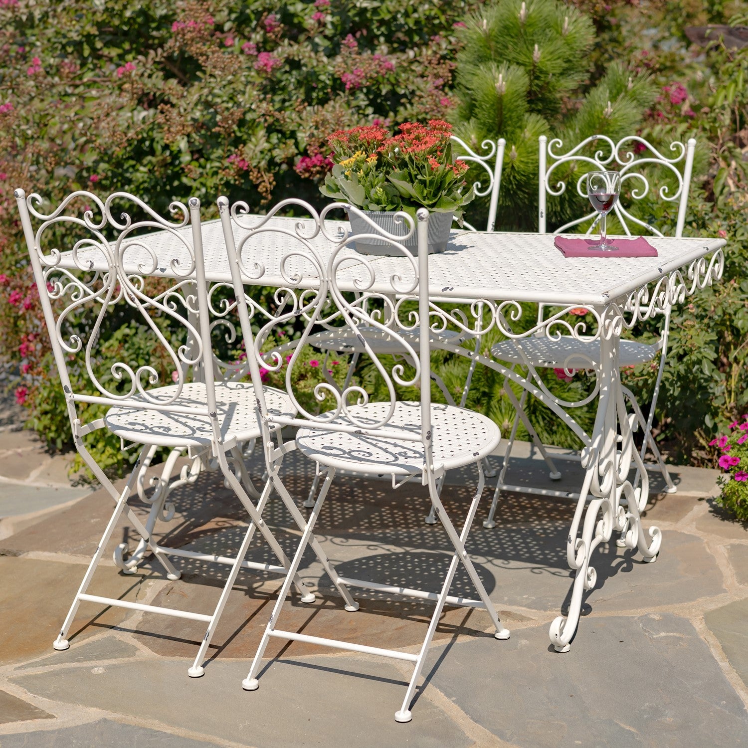 White metal outdoor furniture set with table and chairs on a stone patio