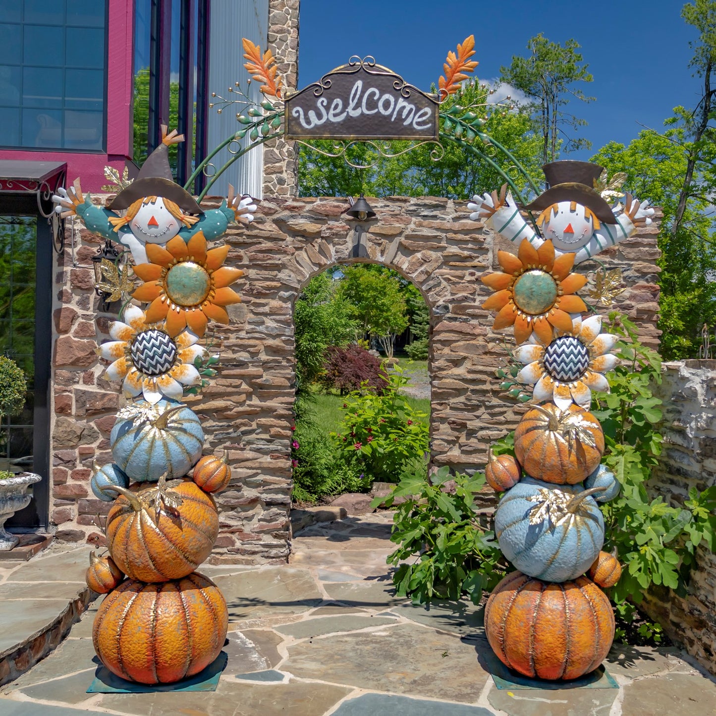 Multiple pumpkins, flowers and scarecrows attached to and forming an iron arch with a welcome sign