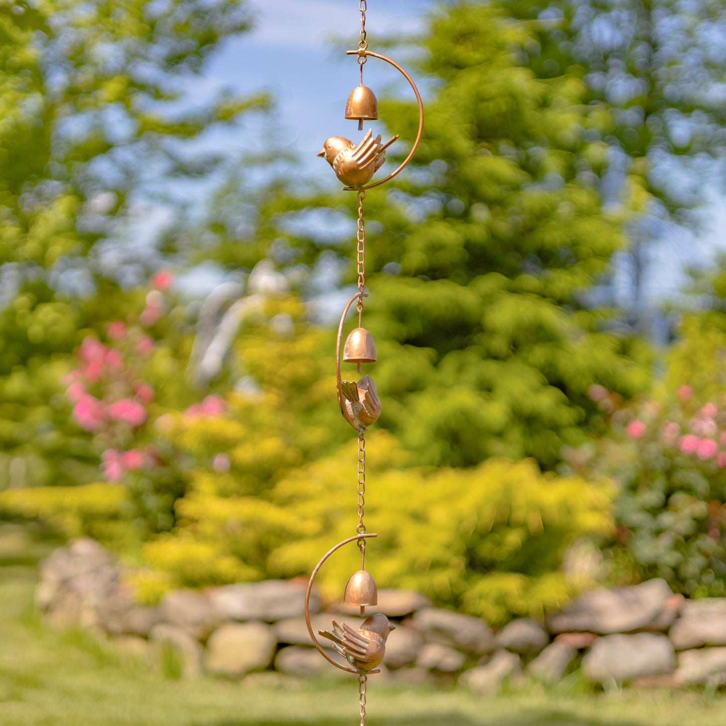 Decorative wind chime with birds and bells against a blurred green background
