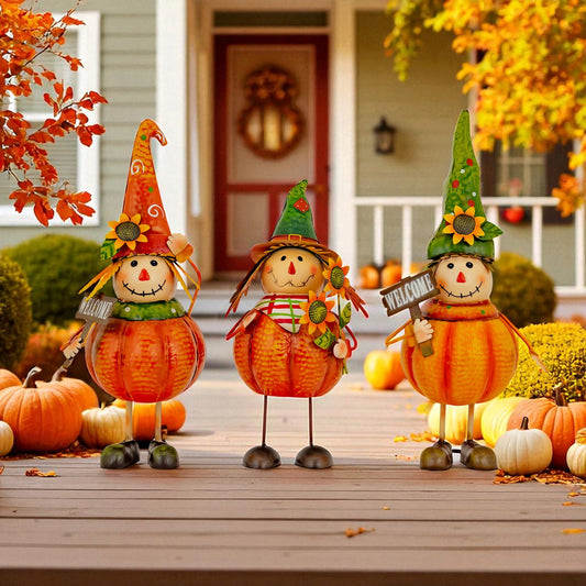 Three decorative autumn scarecrow pumpkins stand on a front porch surrounded by pumpkins and fall leaves. The center pumpkin wears a red hat and holds a small bouquet, while the two side pumpkins wear orange and green pointed hats with sunflower accents.