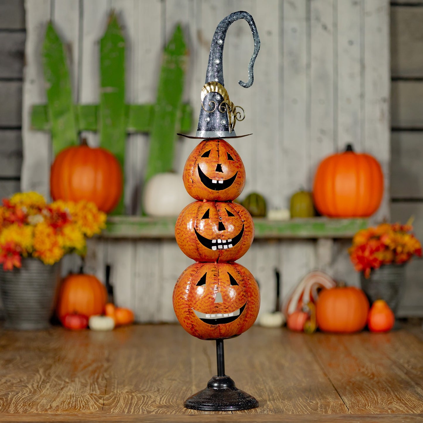 3 carved iron pumpkins stacked on top of each other with a witches hat on top