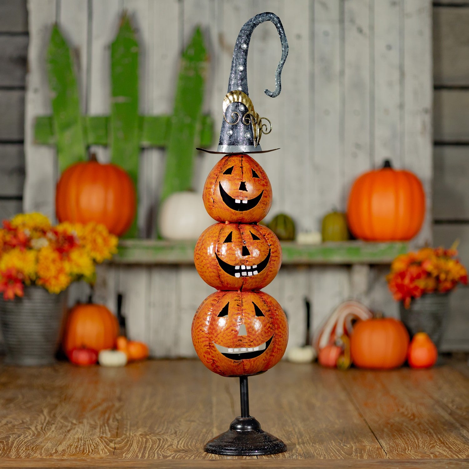 3 carved iron pumpkins stacked on top of each other with a witches hat on top