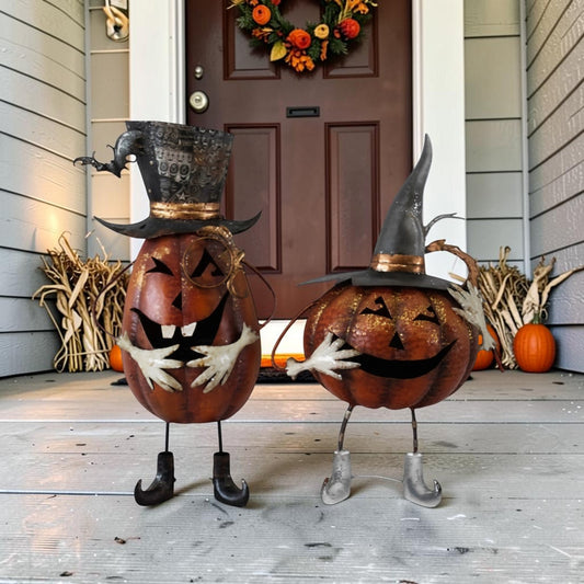 Two Halloween pumpkin decorations with carved faces and witch hats standing on a front porch. One has black legs and boots, and the other has silver legs and boots.