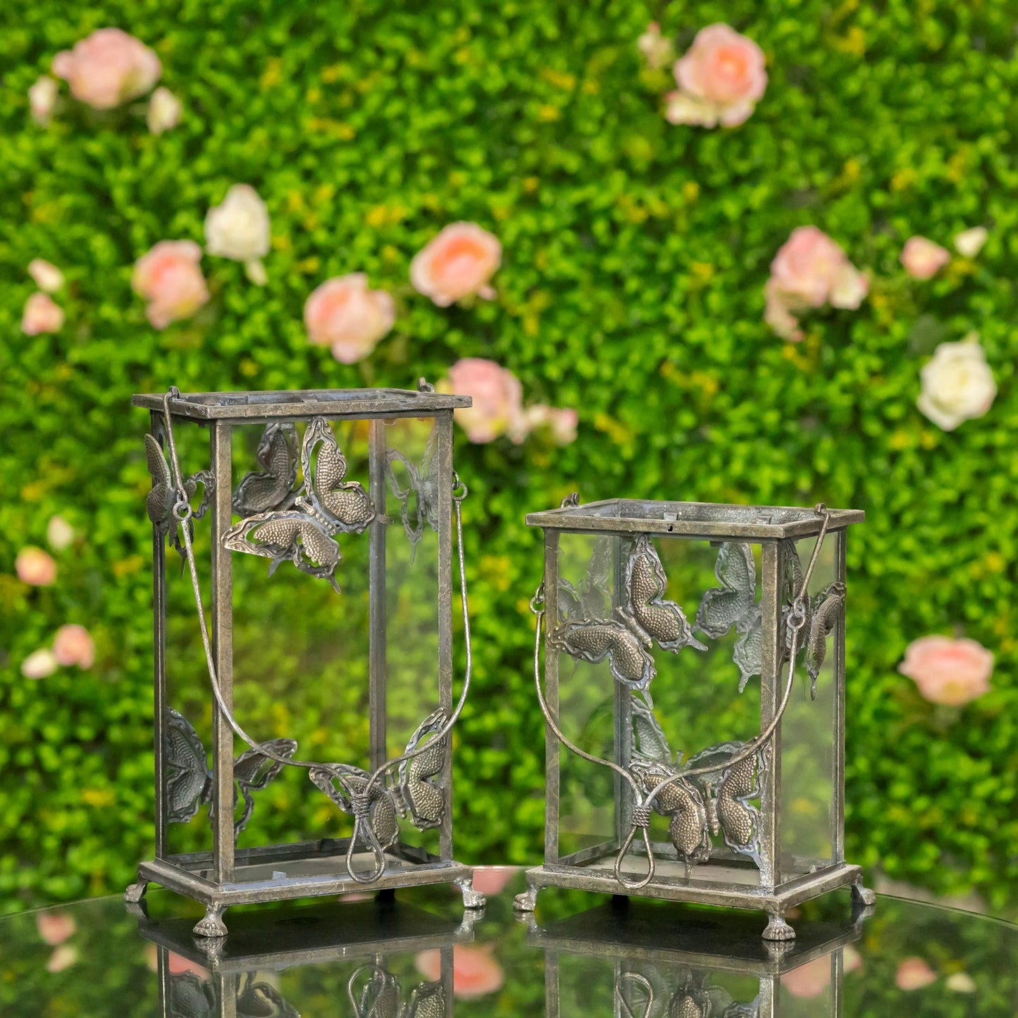 Decorative metal lanterns with floral designs against a green foliage background