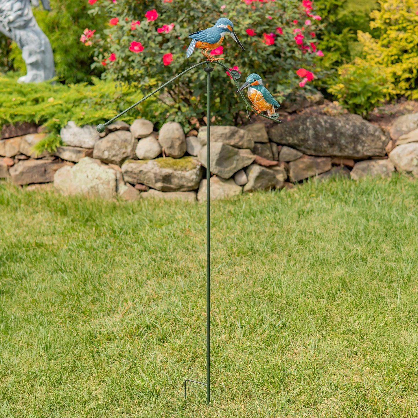 Decorative garden stake with bird figures in a garden setting