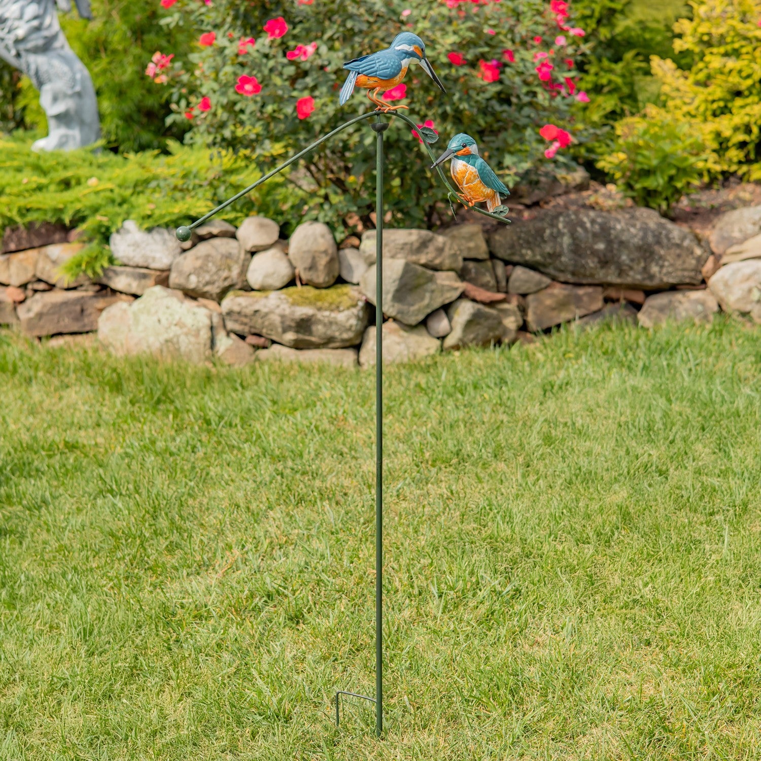 Decorative garden stake with bird figures in a garden setting
