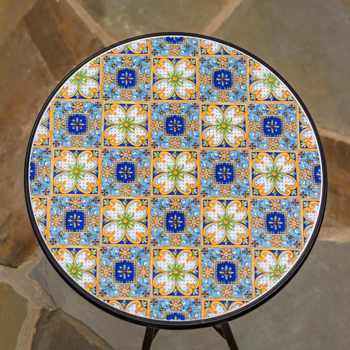 Round outdoor table with a colorful Mediterranean-style tile pattern in blue, orange, green, and white, featuring a black metal frame and legs.