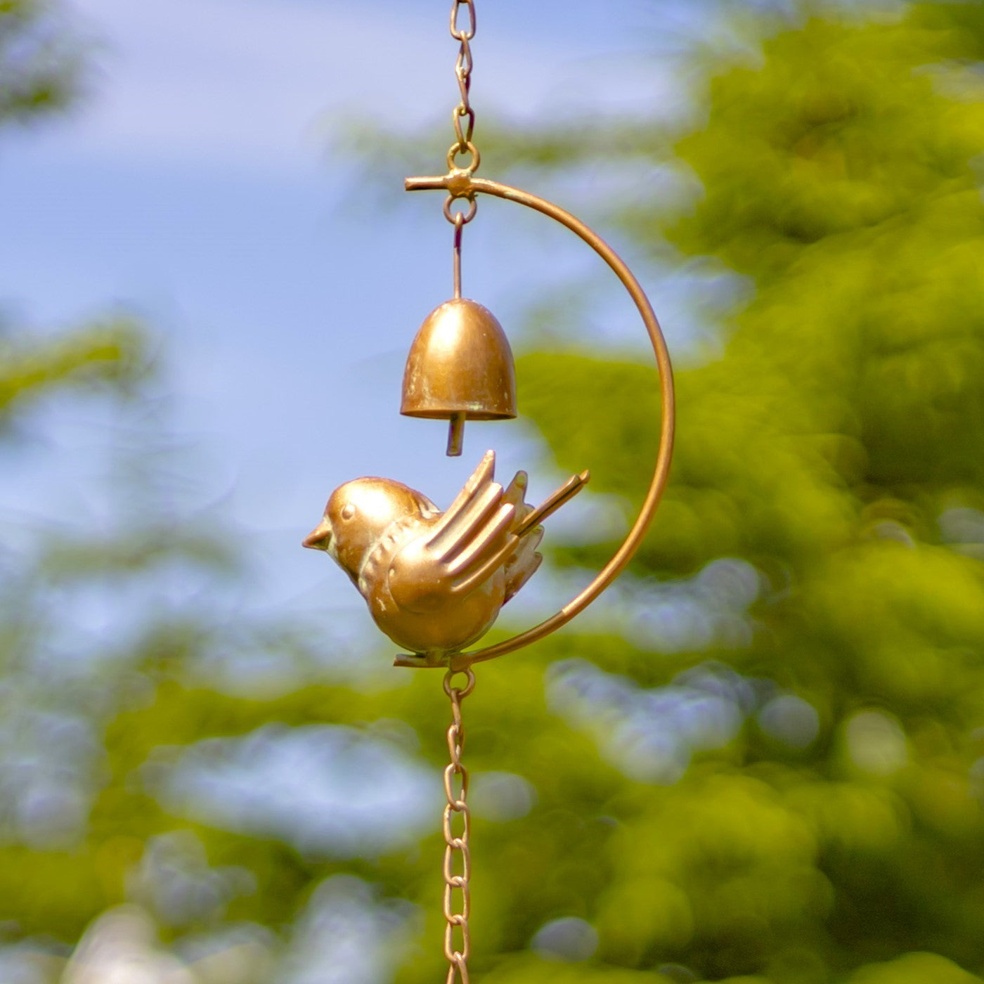 Decorative wind chime with birds and bells against a blurred green background
