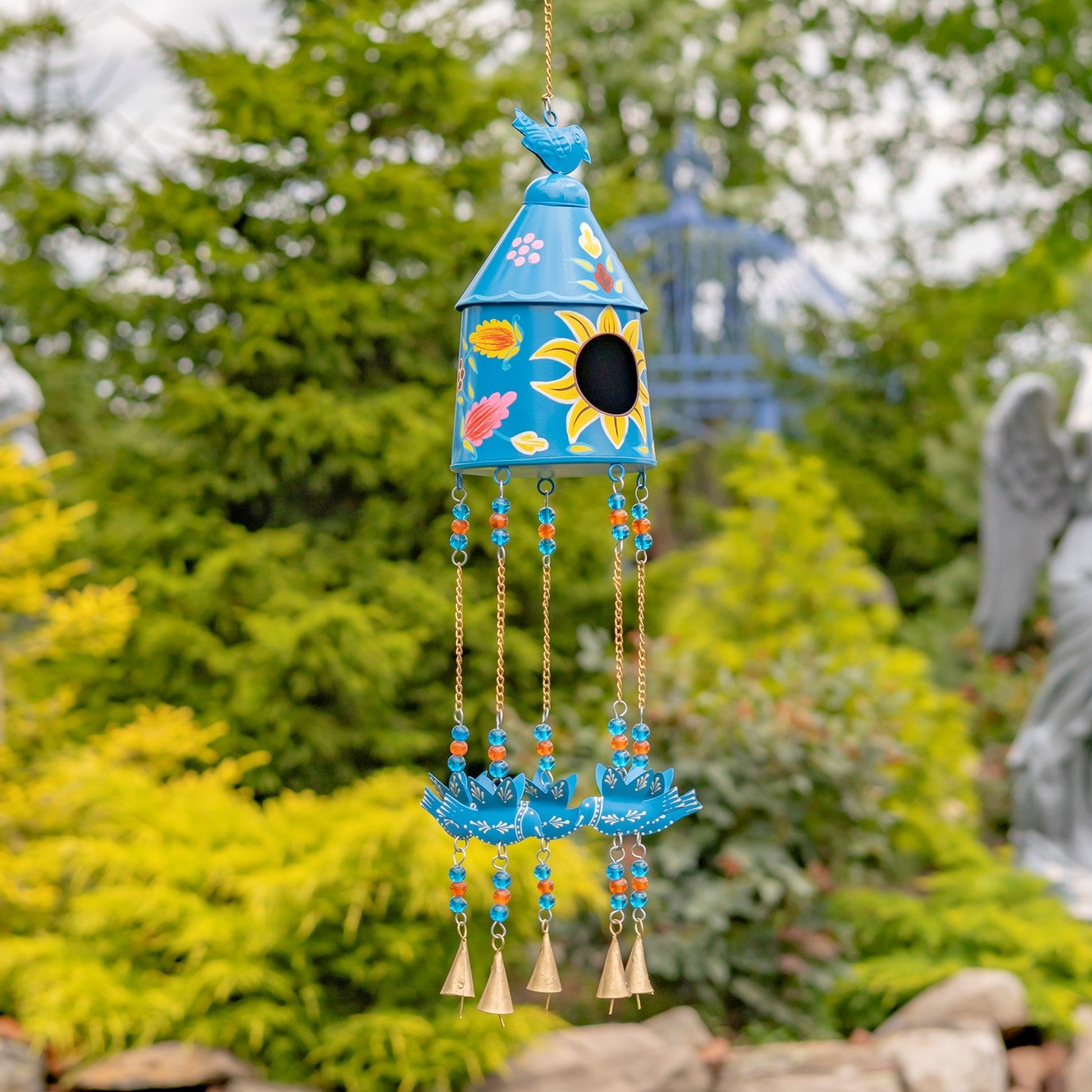 Colorful wind chime with floral designs against a garden background