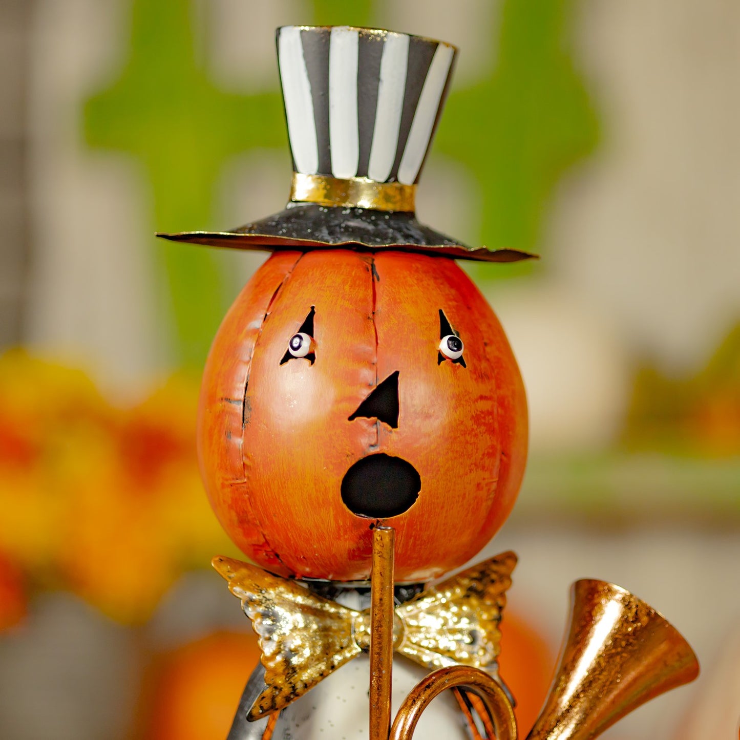 Decorative pumpkin with a top hat, bow tie, and gold accents on a blurred background