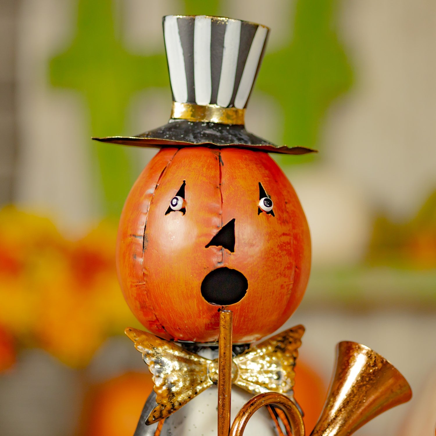 Decorative pumpkin with a top hat, bow tie, and gold accents on a blurred background