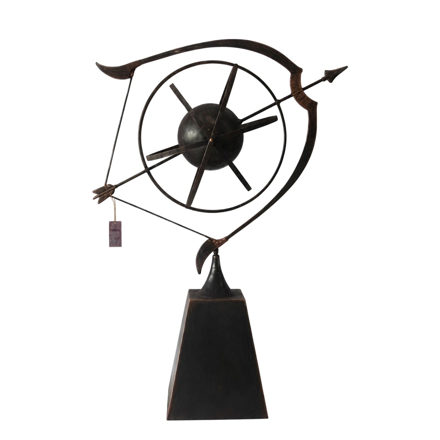 A dark metal abstract sculpture on a black pedestal base, featuring a circular wheel-like form with intersecting lines and a hanging tag, photographed against a plain white background.