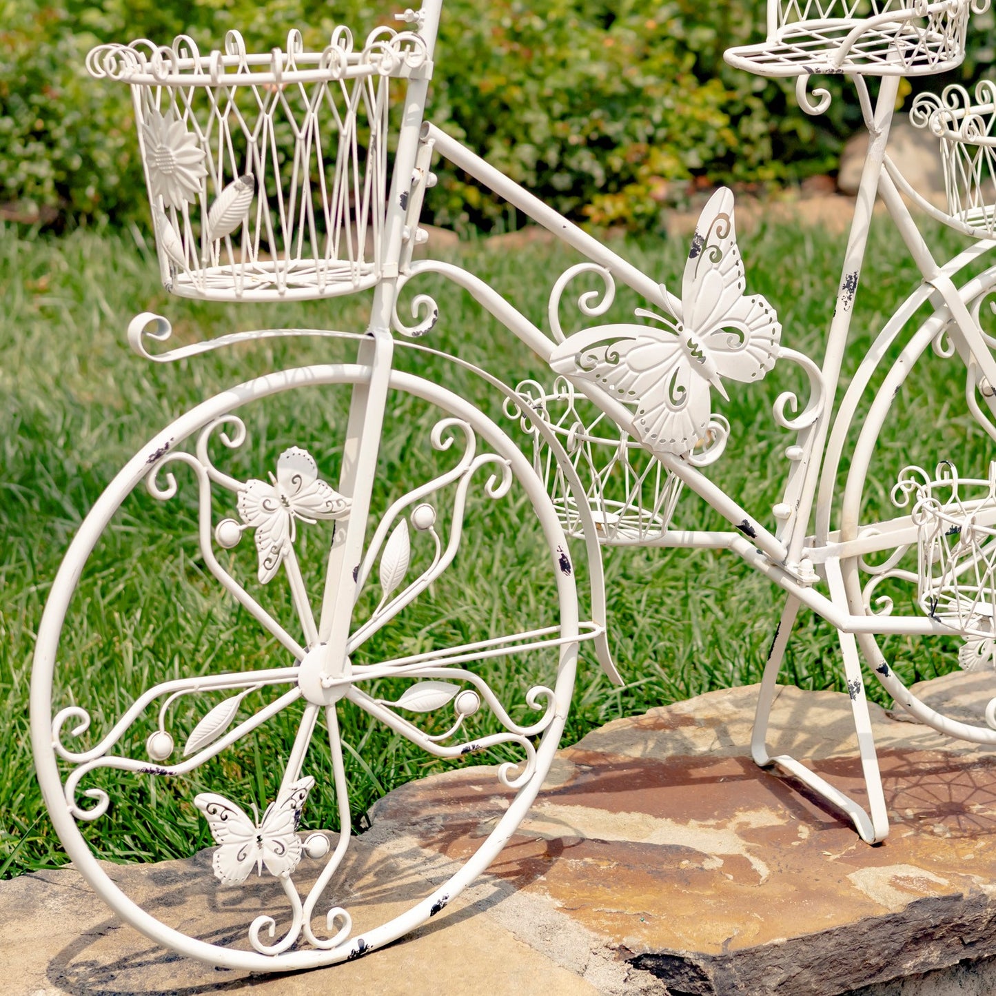 Decorative white metal bicycle with butterfly and bird designs on a grassy background