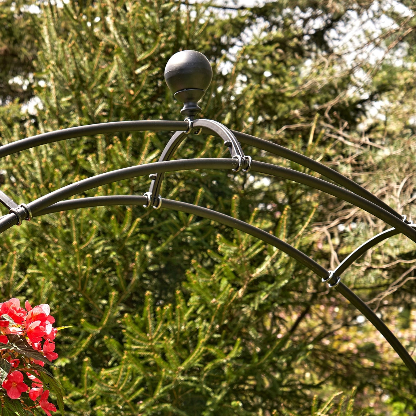 Metal garden arch with floral decorations against a green foliage background