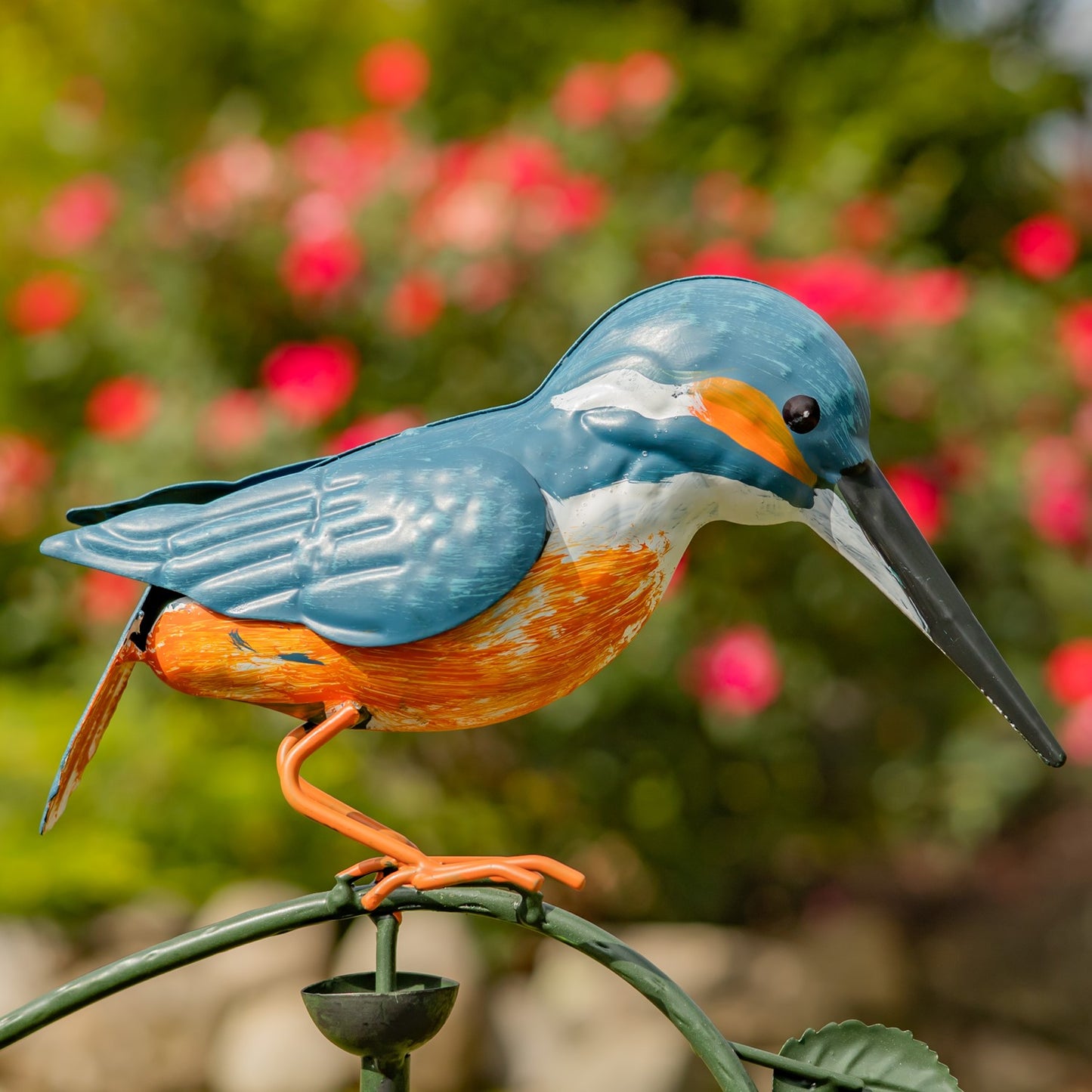 Colorful bird sculpture on a branch with a blurred floral background