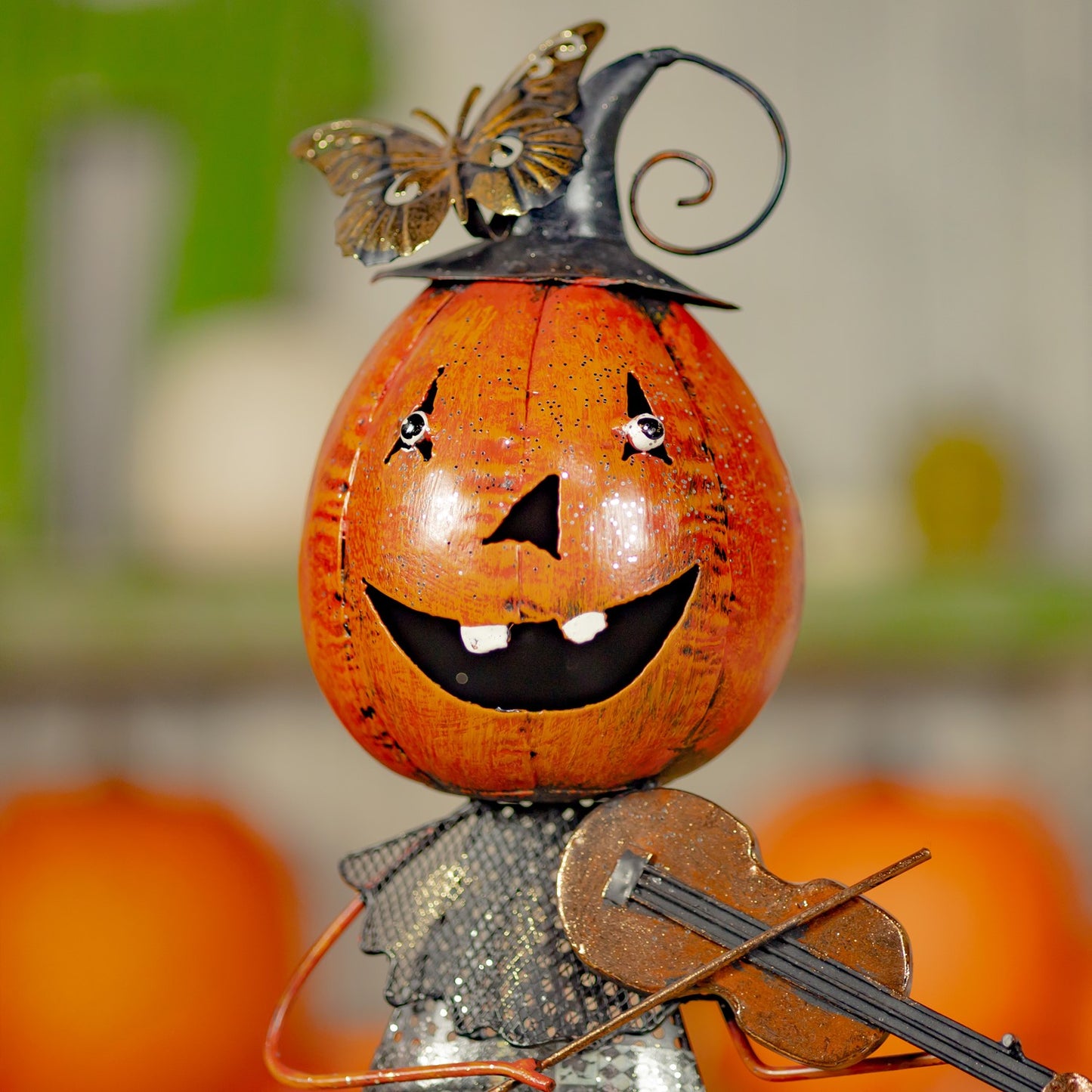 Decorative pumpkin with a face, butterfly, and violin on a blurred background