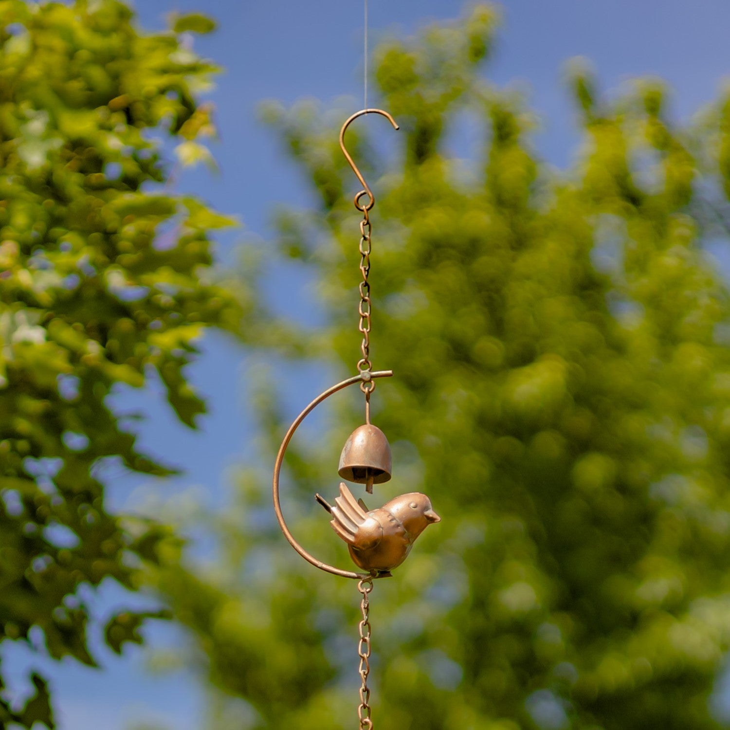 Decorative wind chime with birds and bells against a blurred green background
