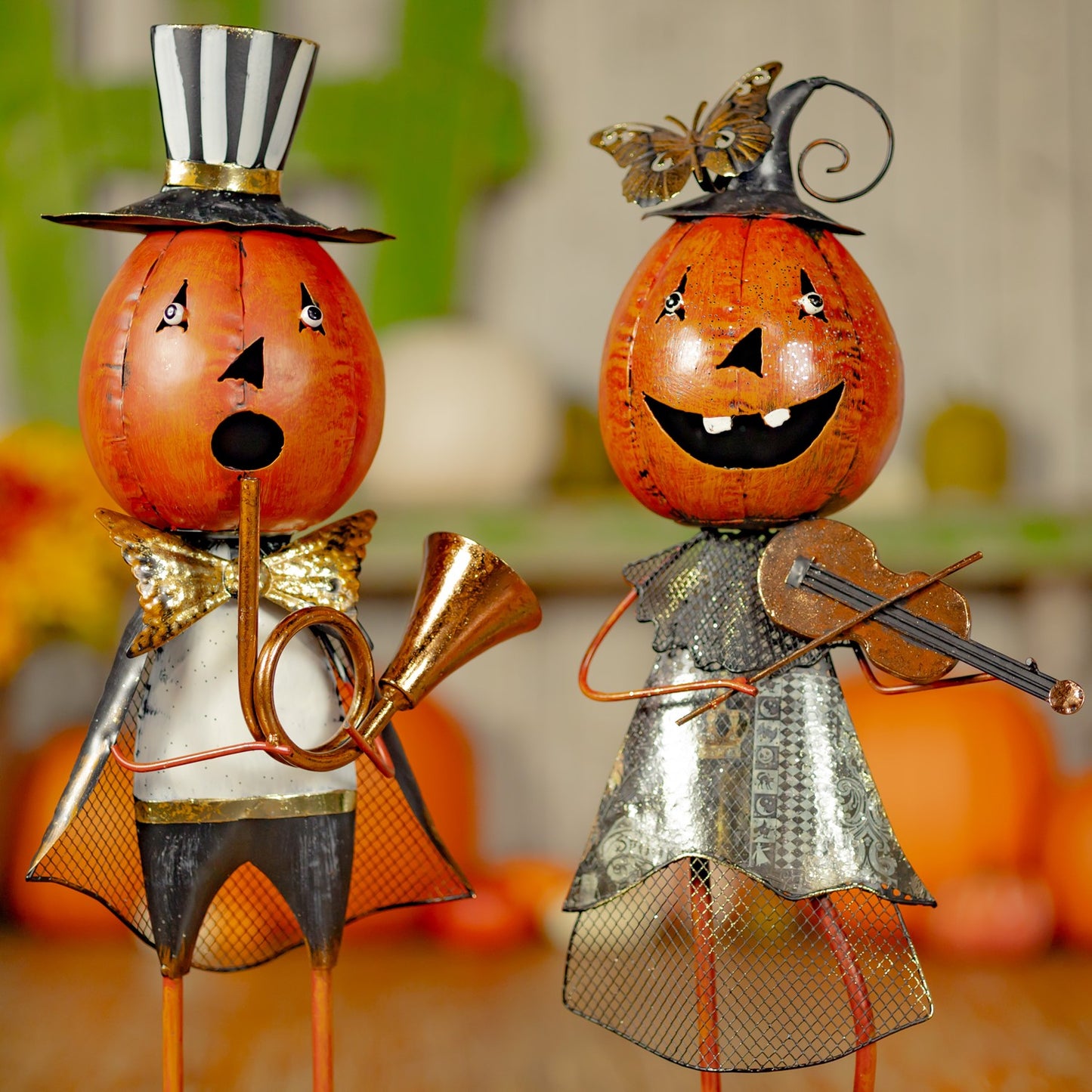 Two decorative pumpkin characters with hats and musical instruments on a blurred background.