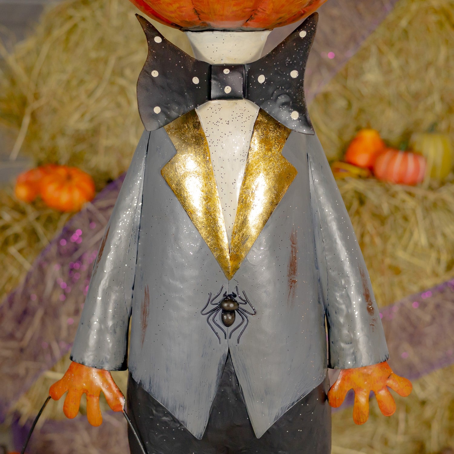Figurine in a Halloween costume with a bow tie and spider design, set against a festive background with pumpkins.