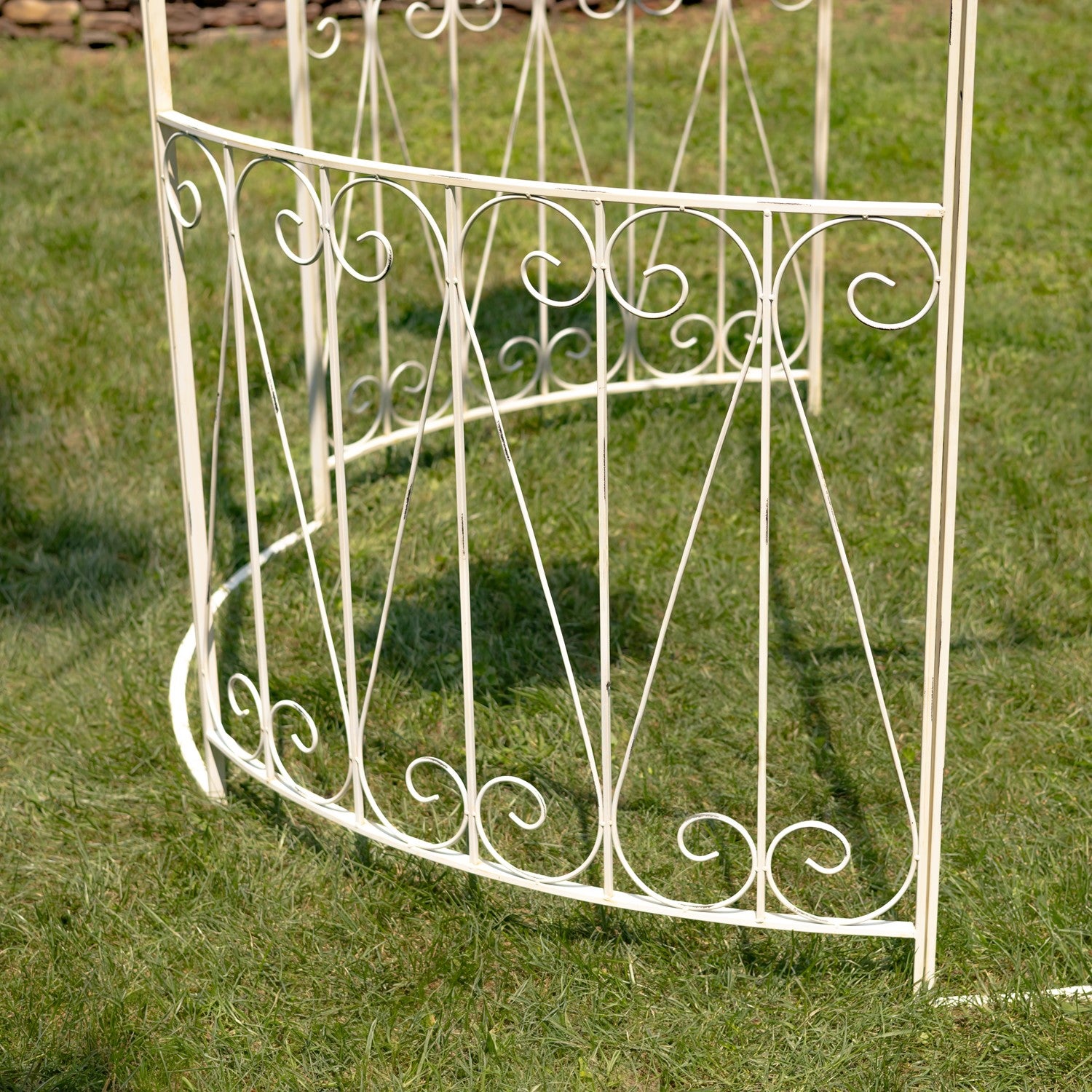 Decorative white metal garden arch on grass