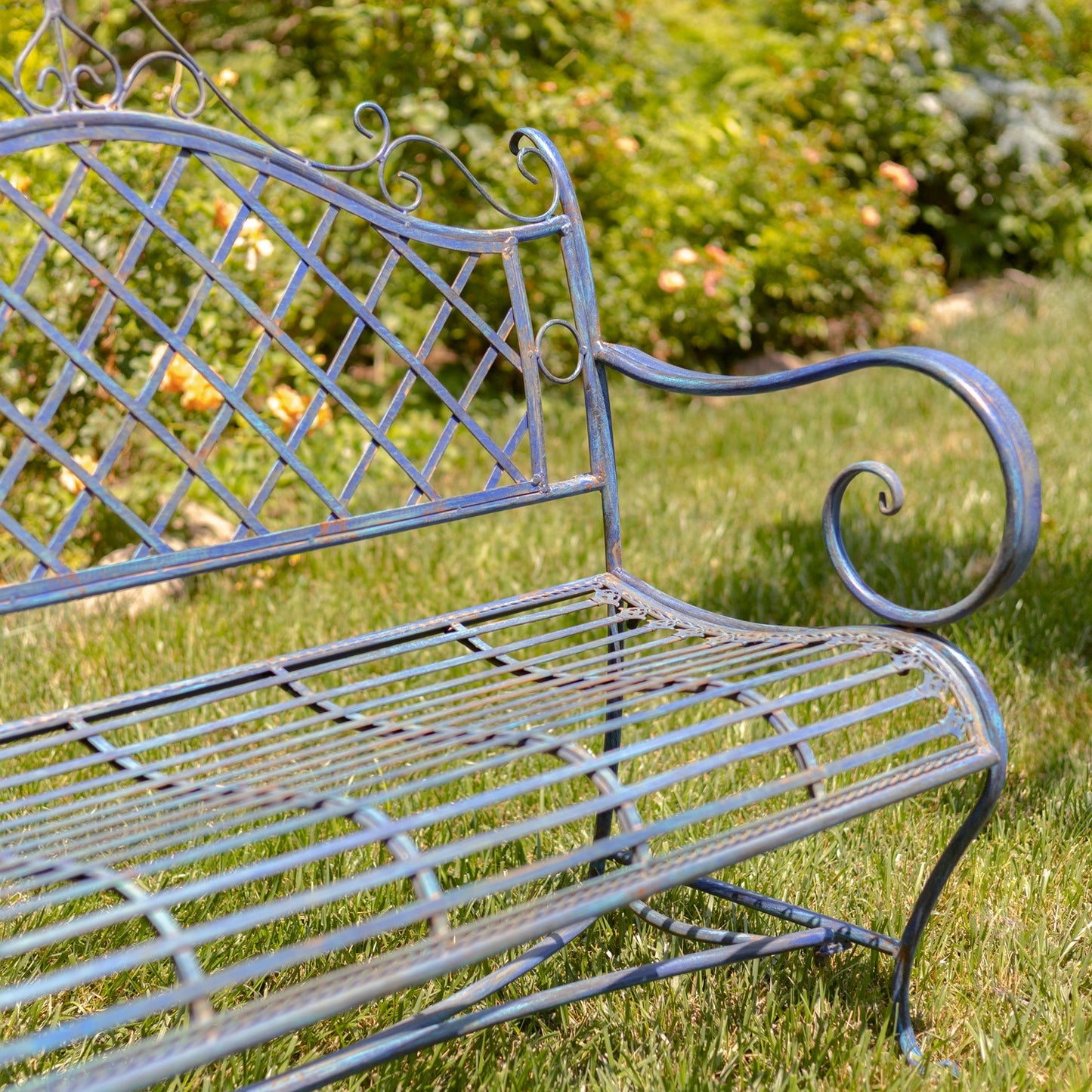 Wrought iron bench in a garden setting with greenery in the background