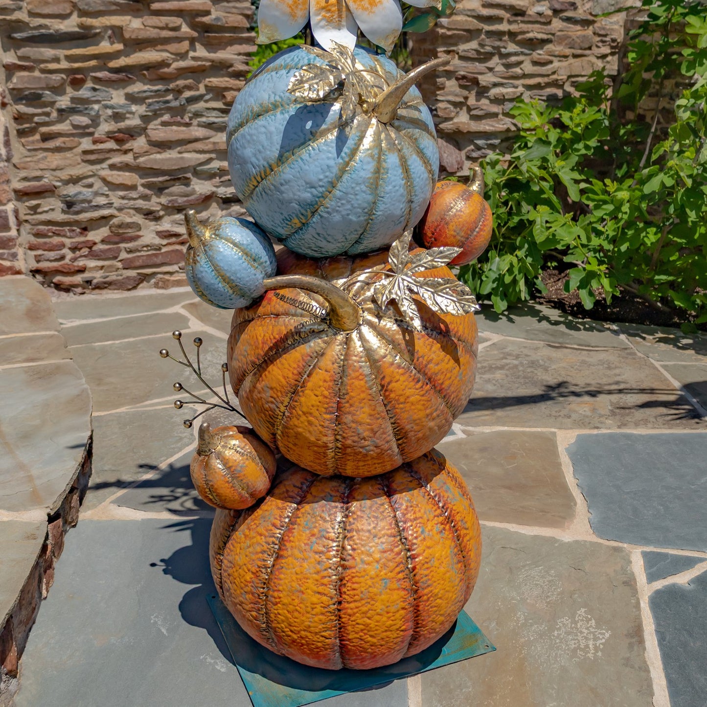 Decorative arrangement of pumpkins with gold accents on a stone surface.