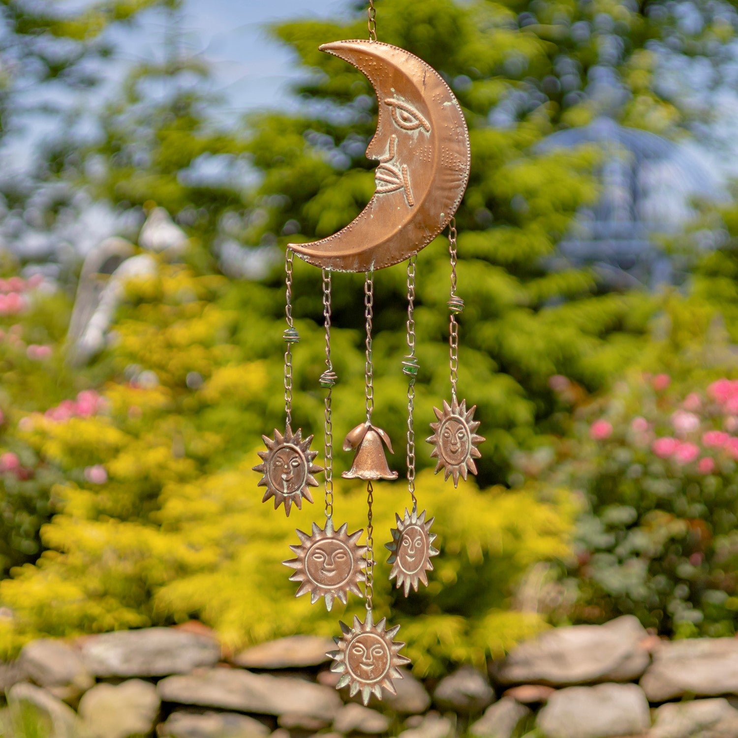 Copper wind chime with celestial design in a garden setting