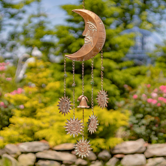 Copper wind chime with celestial design in a garden setting