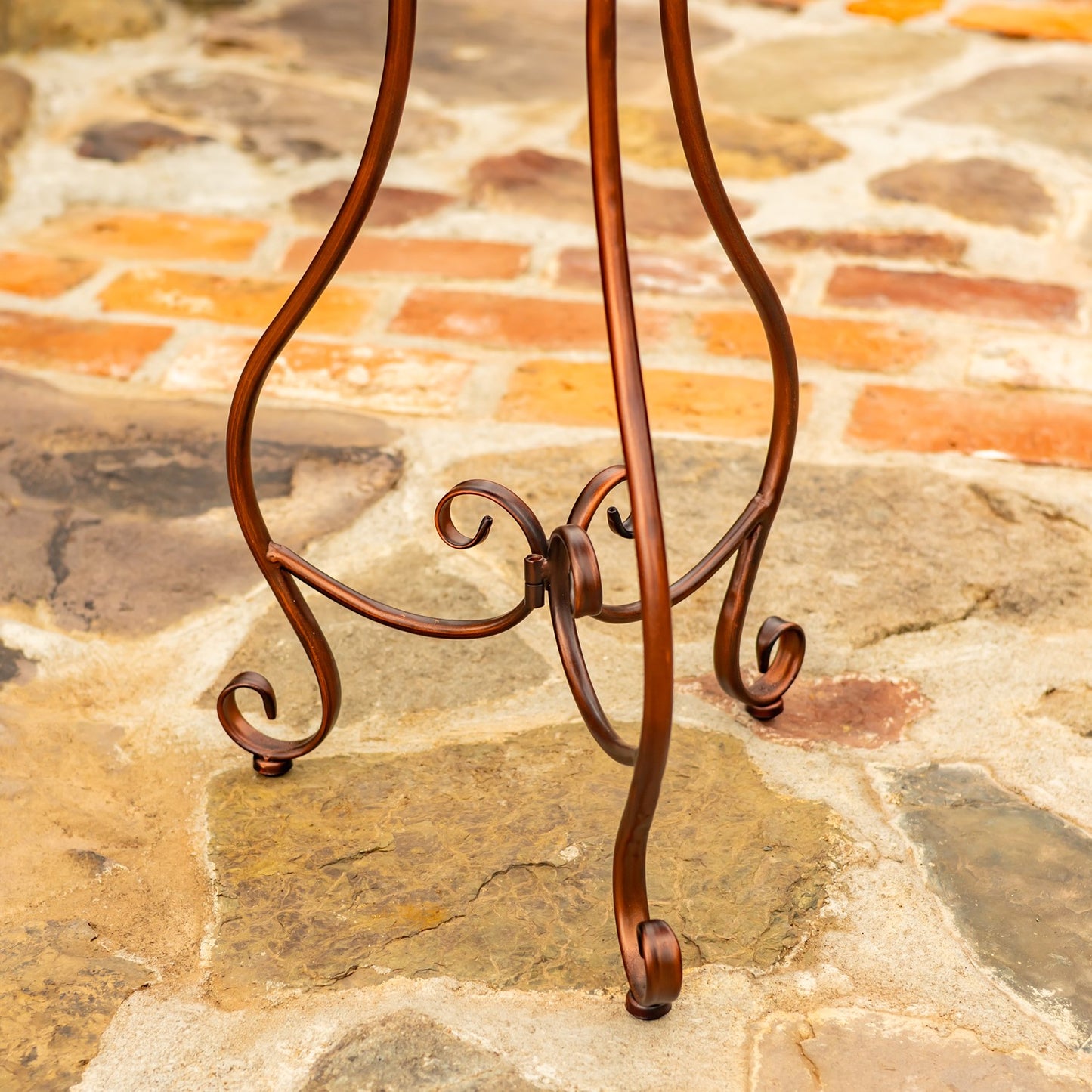 Flower shaped birdbath with ivy and birds sitting on the side in a garden setting